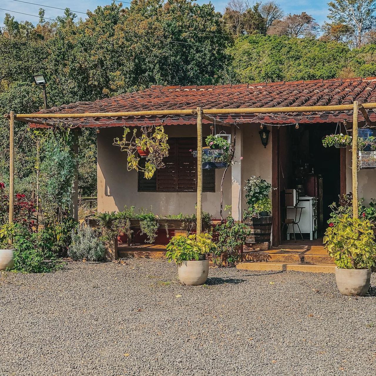 A casa da loja do sítio, com varanda de telhas e vasos de flores