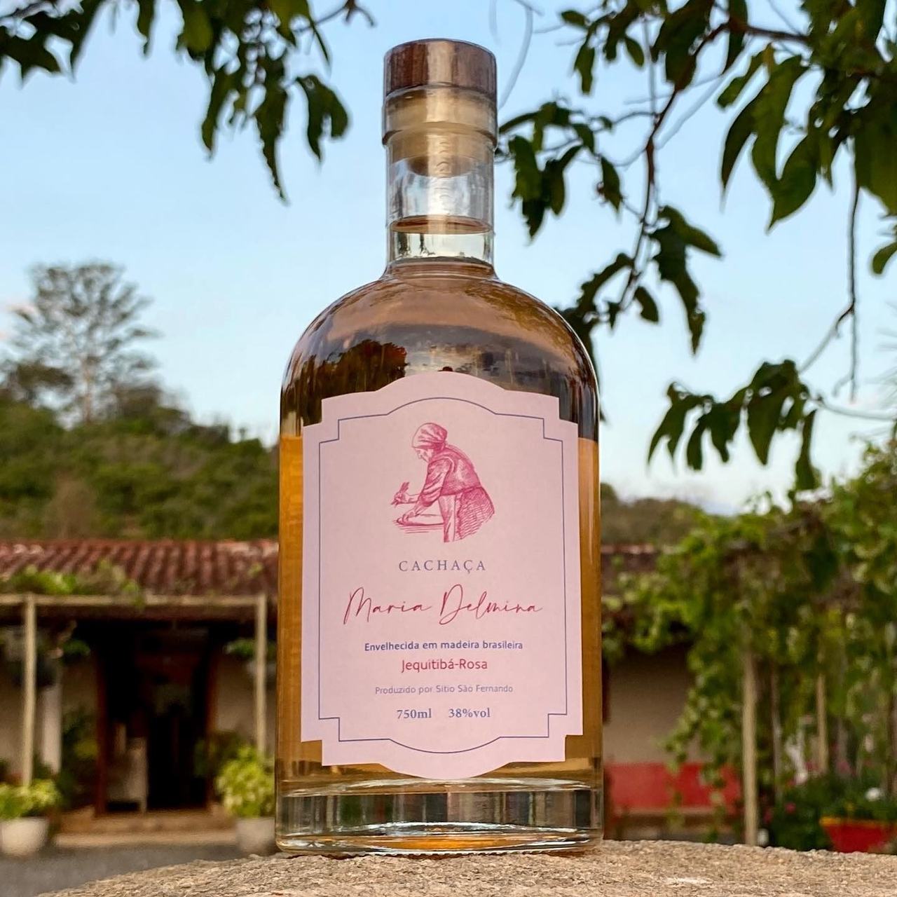 Garrafa da cachaça Maria Delmina diante do barril