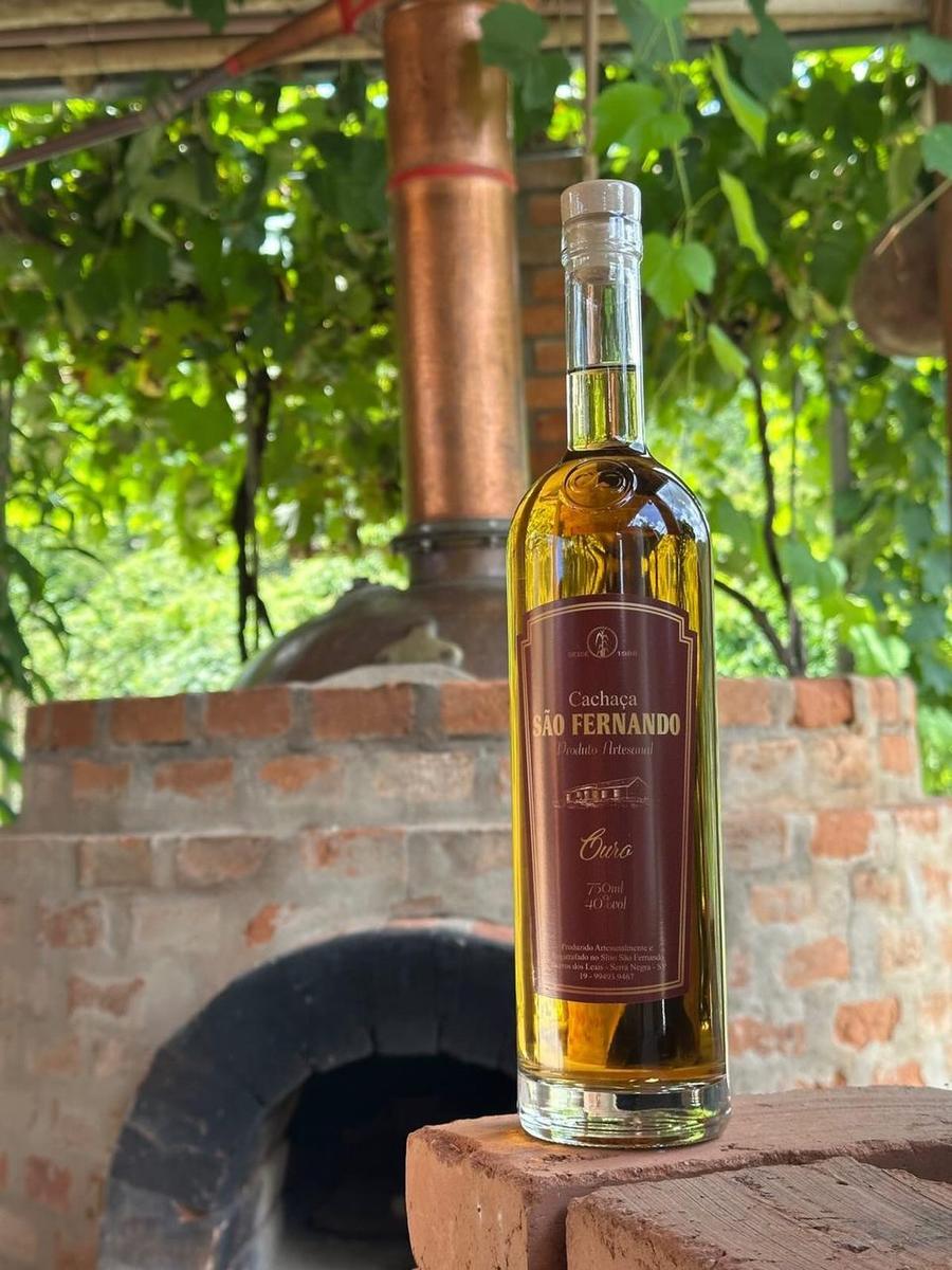 Garrafa de Cachaça Ouro São Fernando diante do forno de tijolos