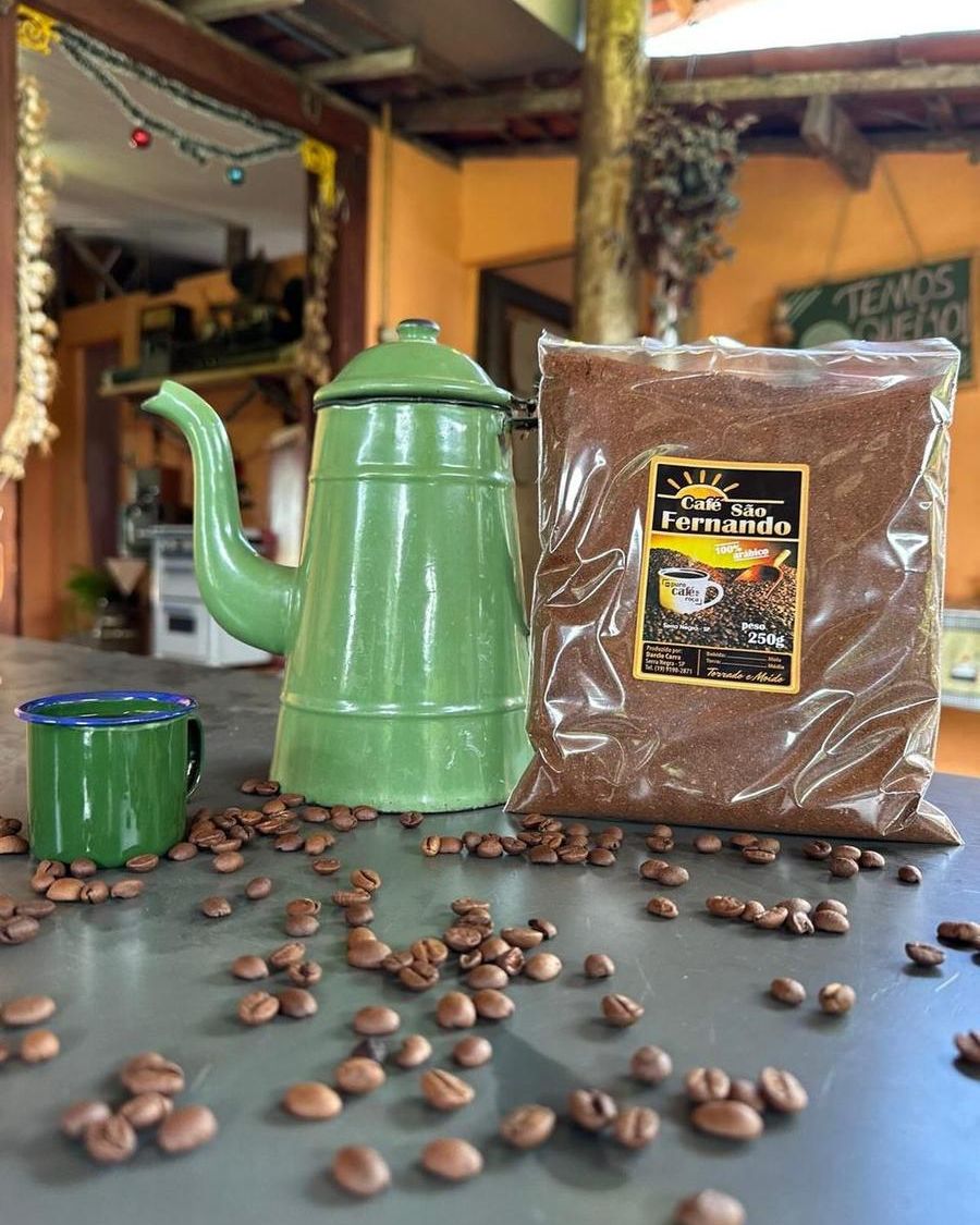 Pacote de Café Premium São Fernando com um bule esmaltado verde e grãos sobre a mesa