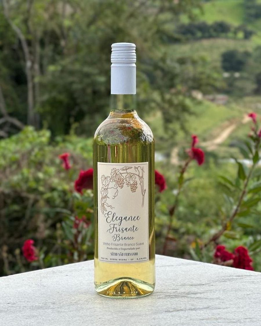 Garrafa de Elegance Frisante Branco entre flores, com a serra ao fundo