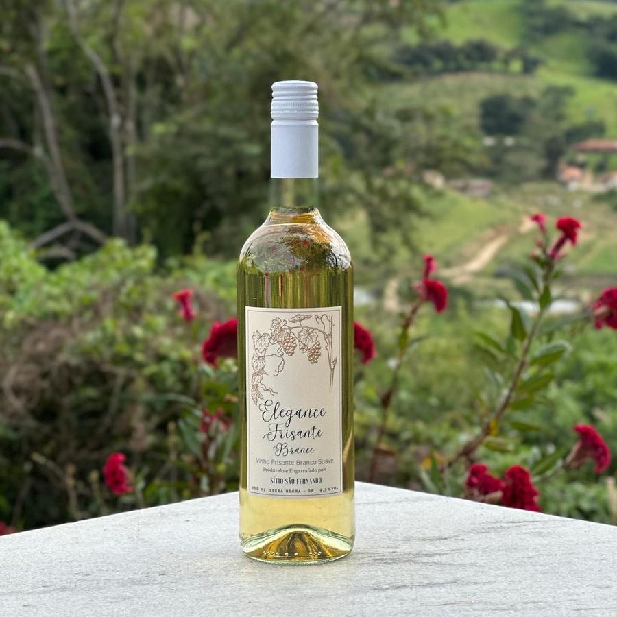 Garrafa de Elegance Frisante Branco entre flores, com a serra ao fundo