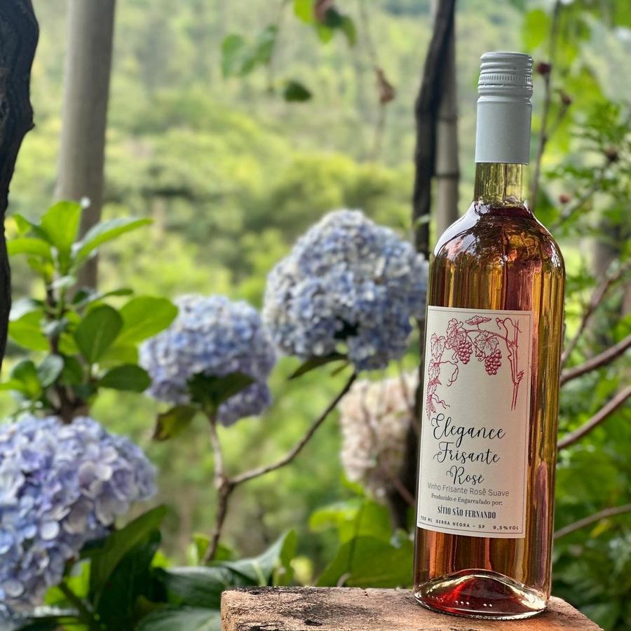 Garrafa de Elegance Frisante Rosé ao lado de hortênsias