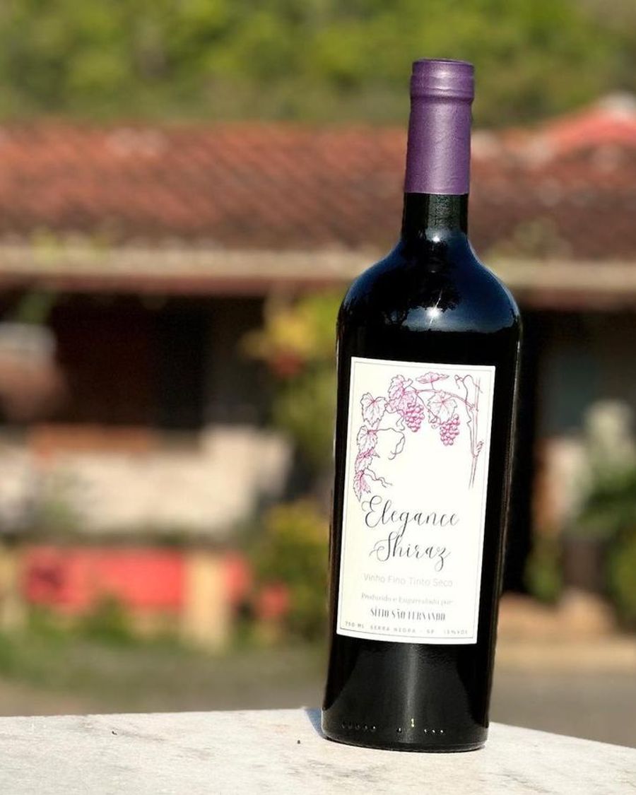 Garrafa de Elegance Shiraz com a casa do sítio ao fundo