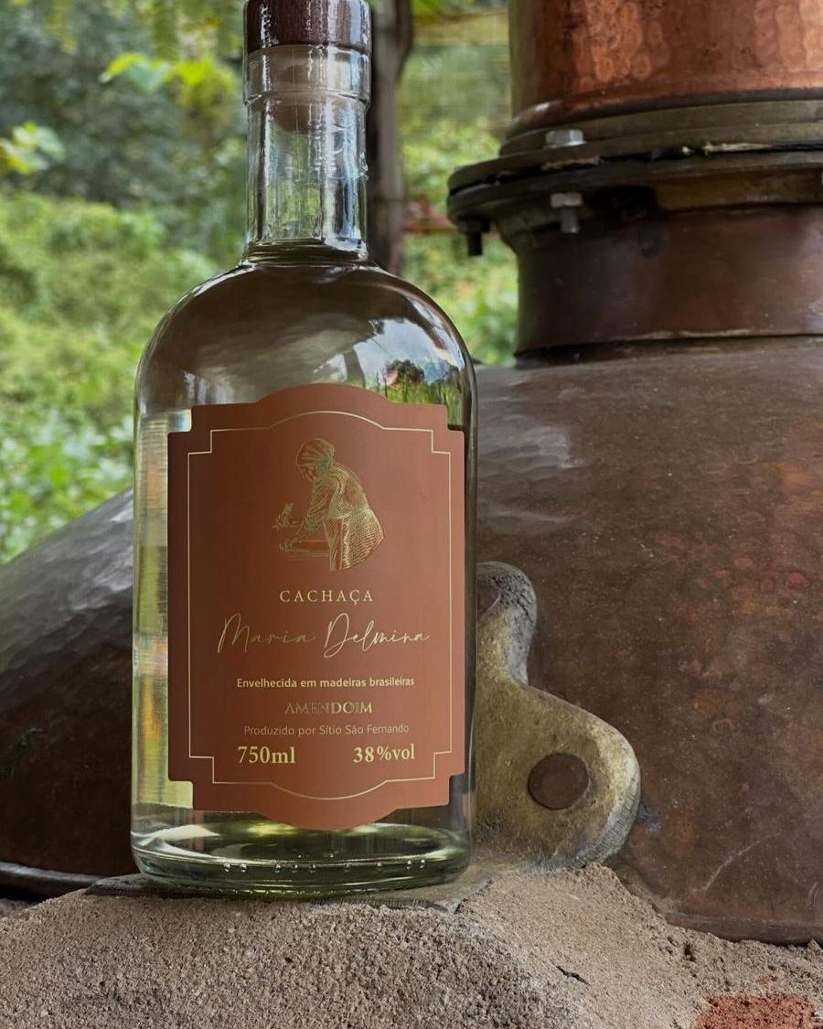 Garrafa da cachaça Maria Delmina Amendoim diante do alambique