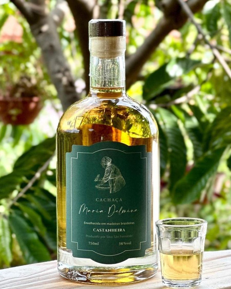 Garrafa da cachaça Maria Delmina Castanheira com um copinho servido