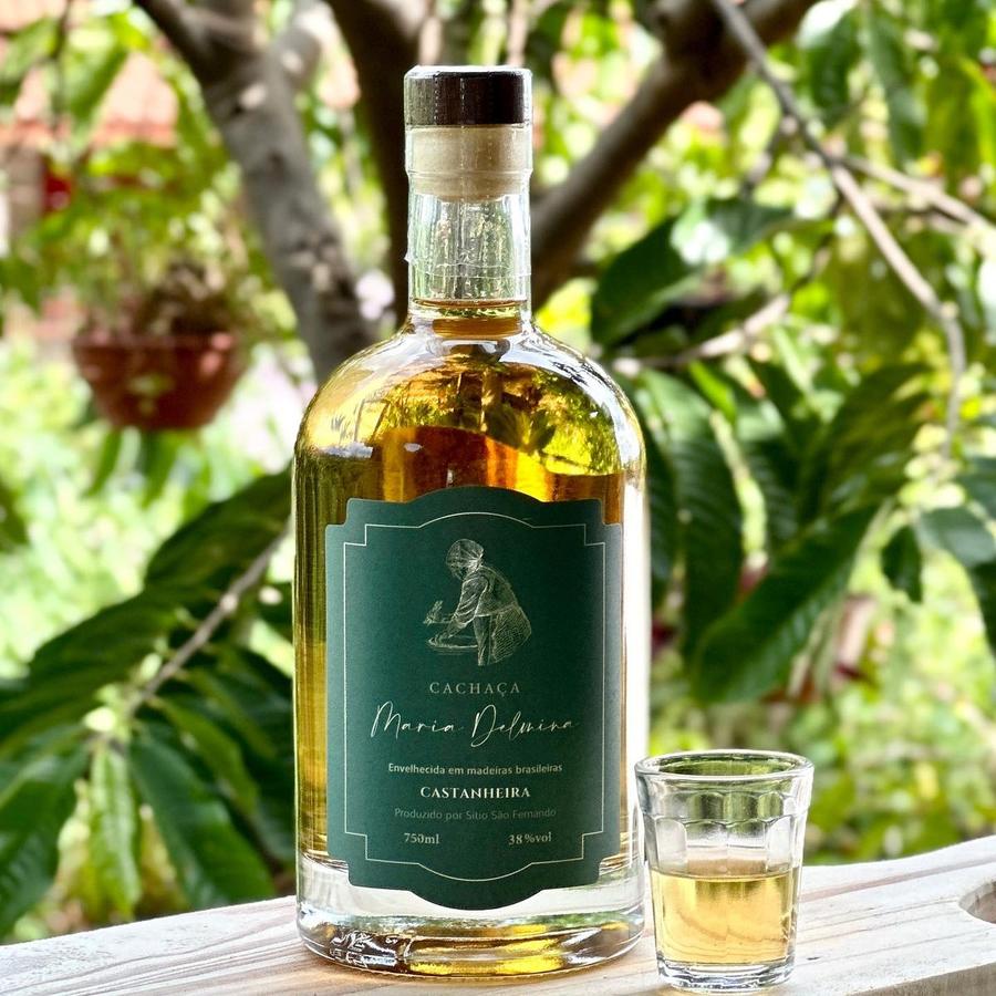 Garrafa da cachaça Maria Delmina Castanheira com um copinho servido