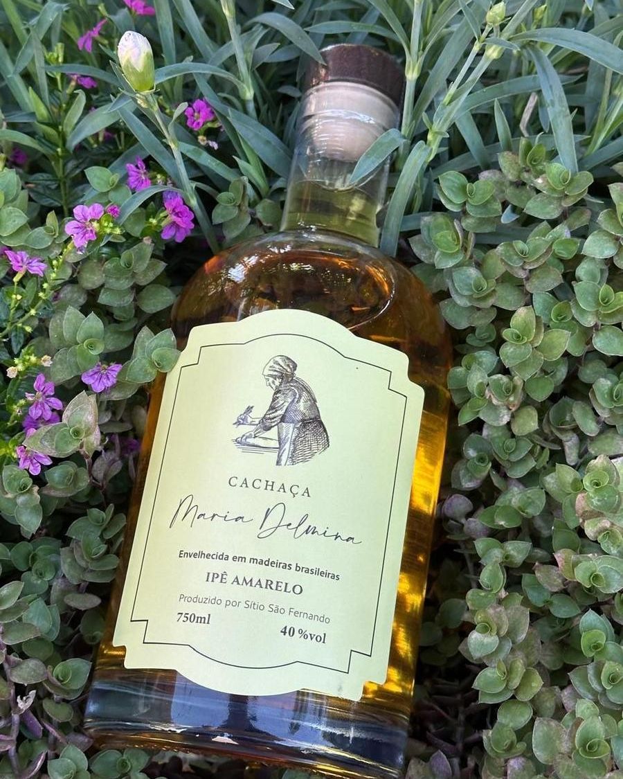 Garrafa da cachaça Maria Delmina Ipê Amarelo entre flores