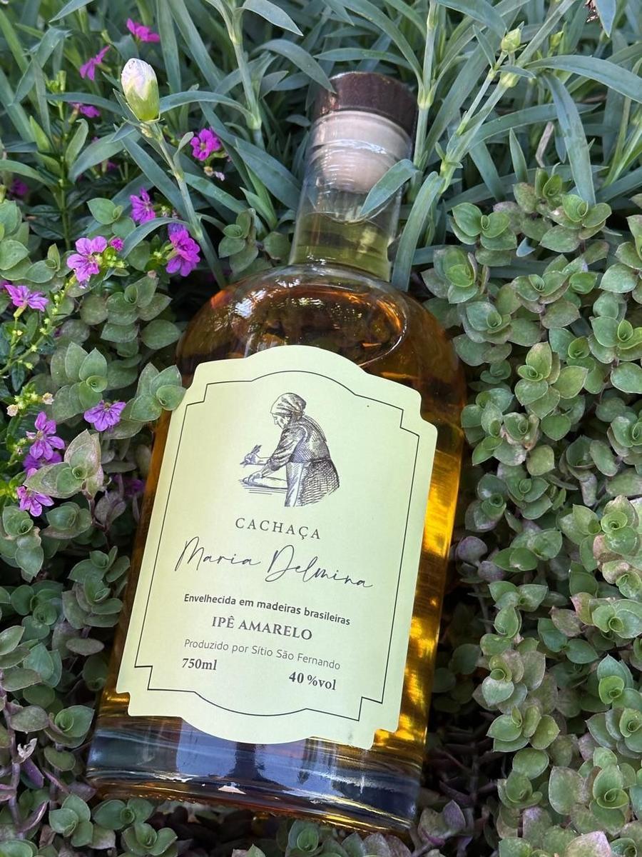 Garrafa da cachaça Maria Delmina Ipê Amarelo entre flores