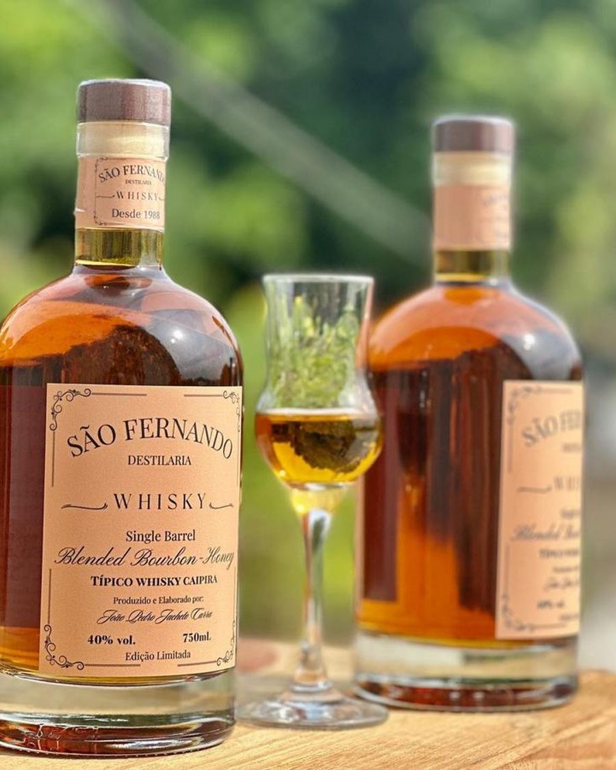 Duas garrafas do Típico Whisky Caipira com um copo servido